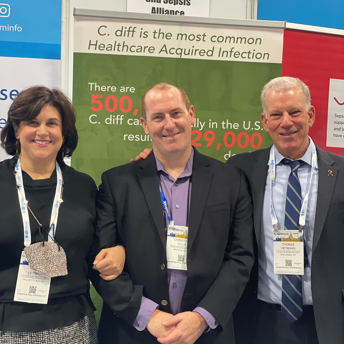 Three smiling people in front of an educational poster.