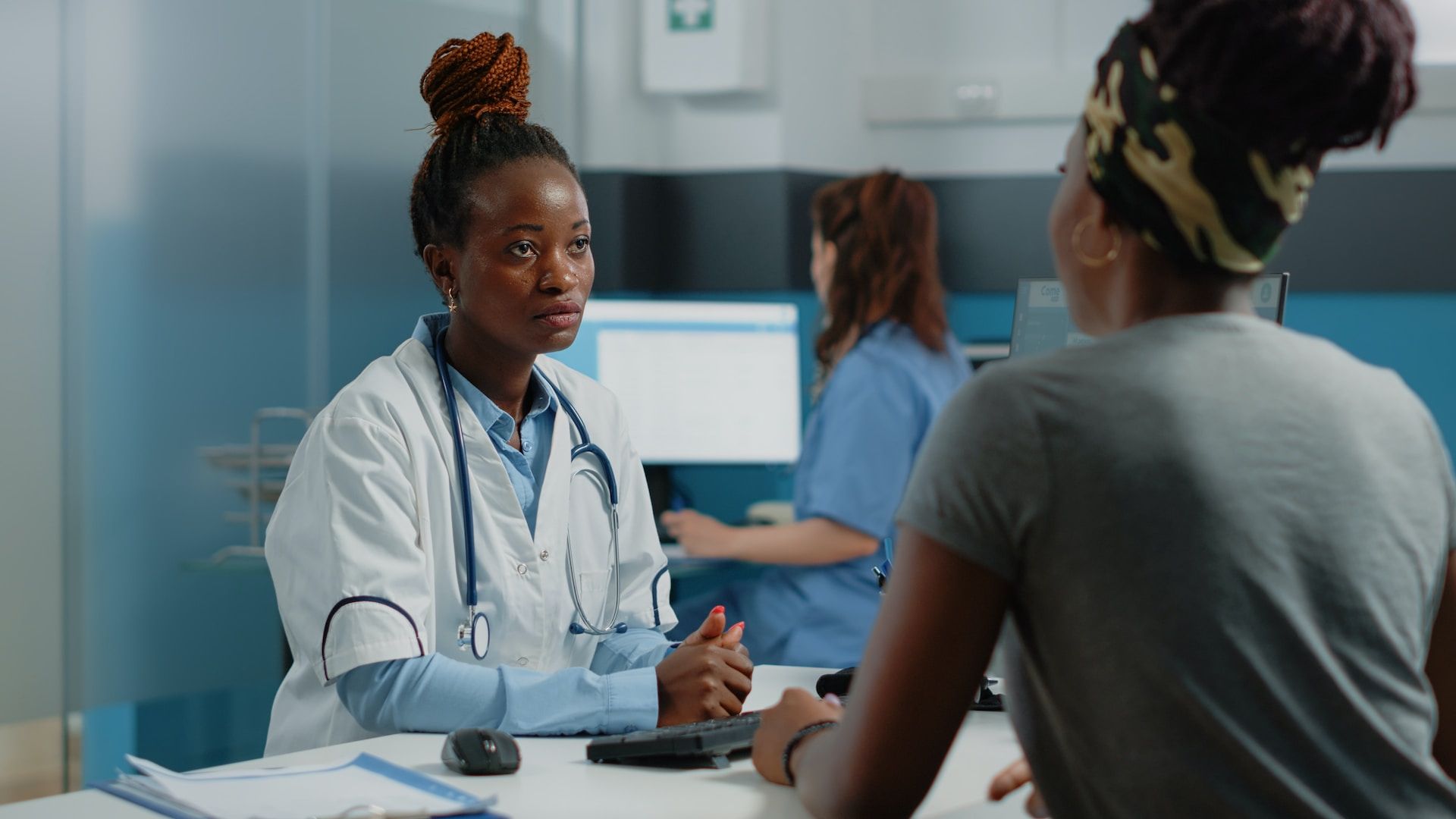 Doctor advising patient with aide in background.